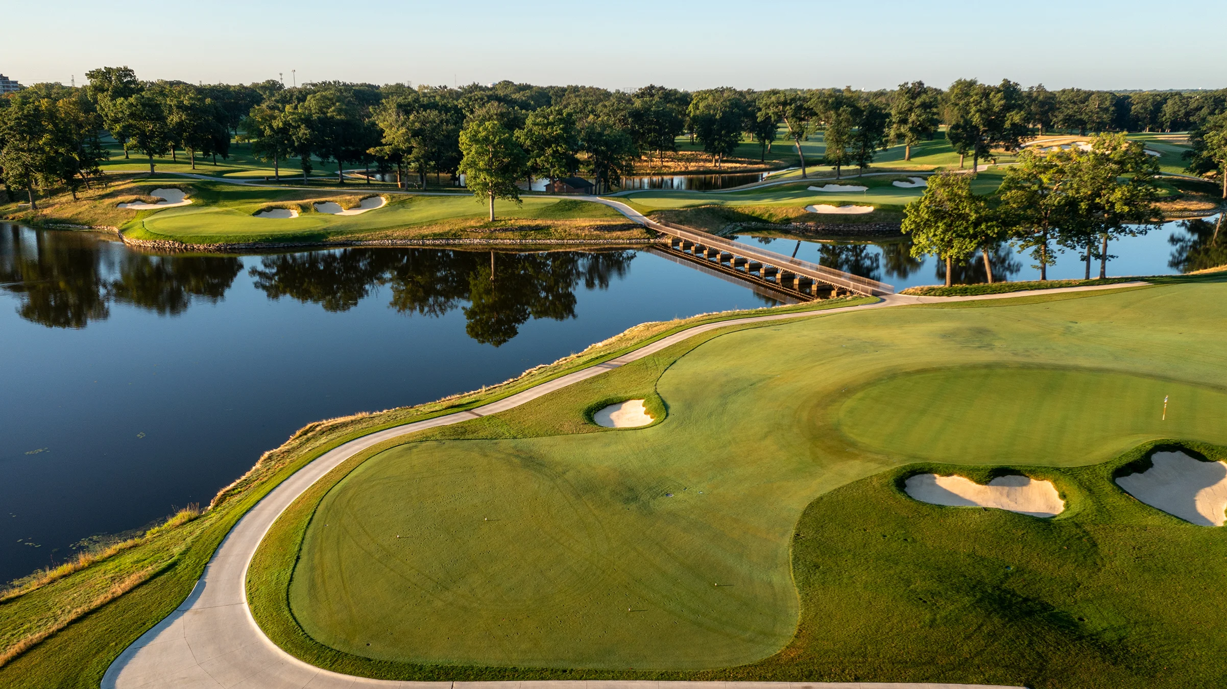 Sân golf với hồ nước và cầu gỗ làm hình nền điện thoại