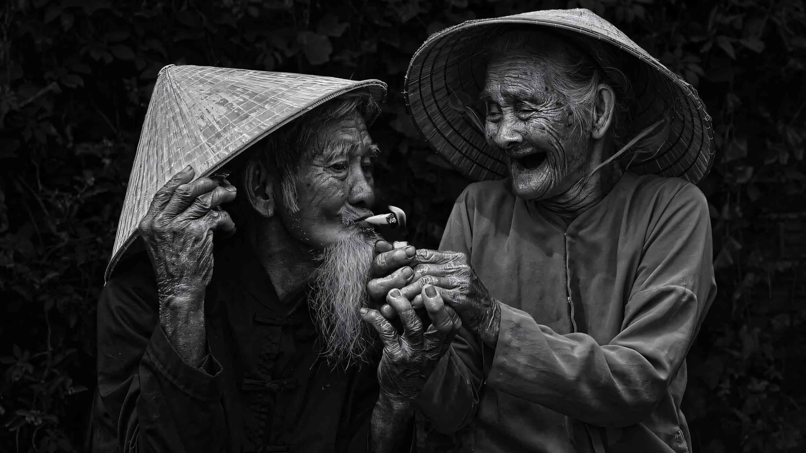 Hai người lớn tuổi đội nón lá bật cười vui vẻ trong khoảnh khắc đời thường